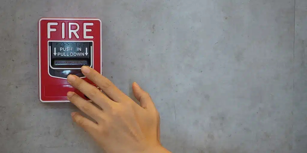 a hand pressing a fire alarm button