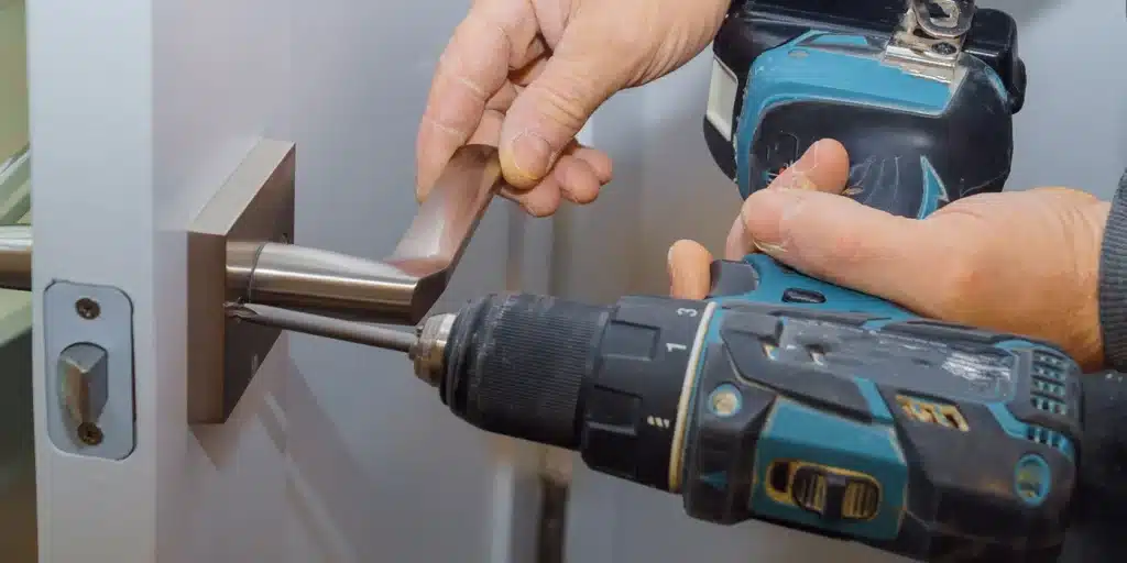 a person using a drill to drill a door handle