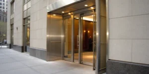 Installing a commercial entry door on a modern building with a glass and metal frame.