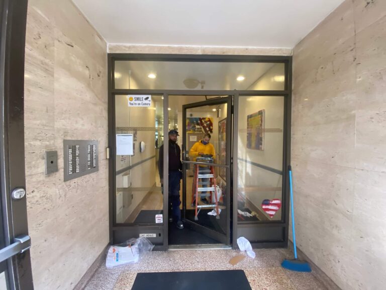 Golden Key Locksmith NYC technicians at a Manhattan apartment building entrance preparing for a door repair