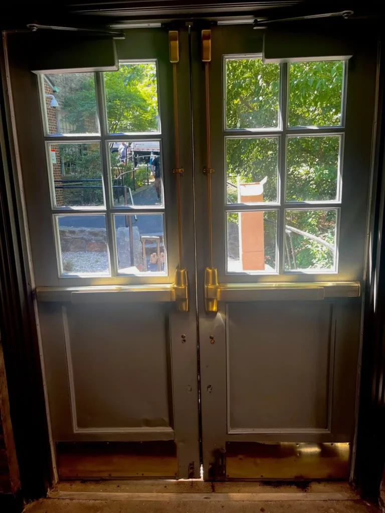 Double residential doors with brass push bars and window panes