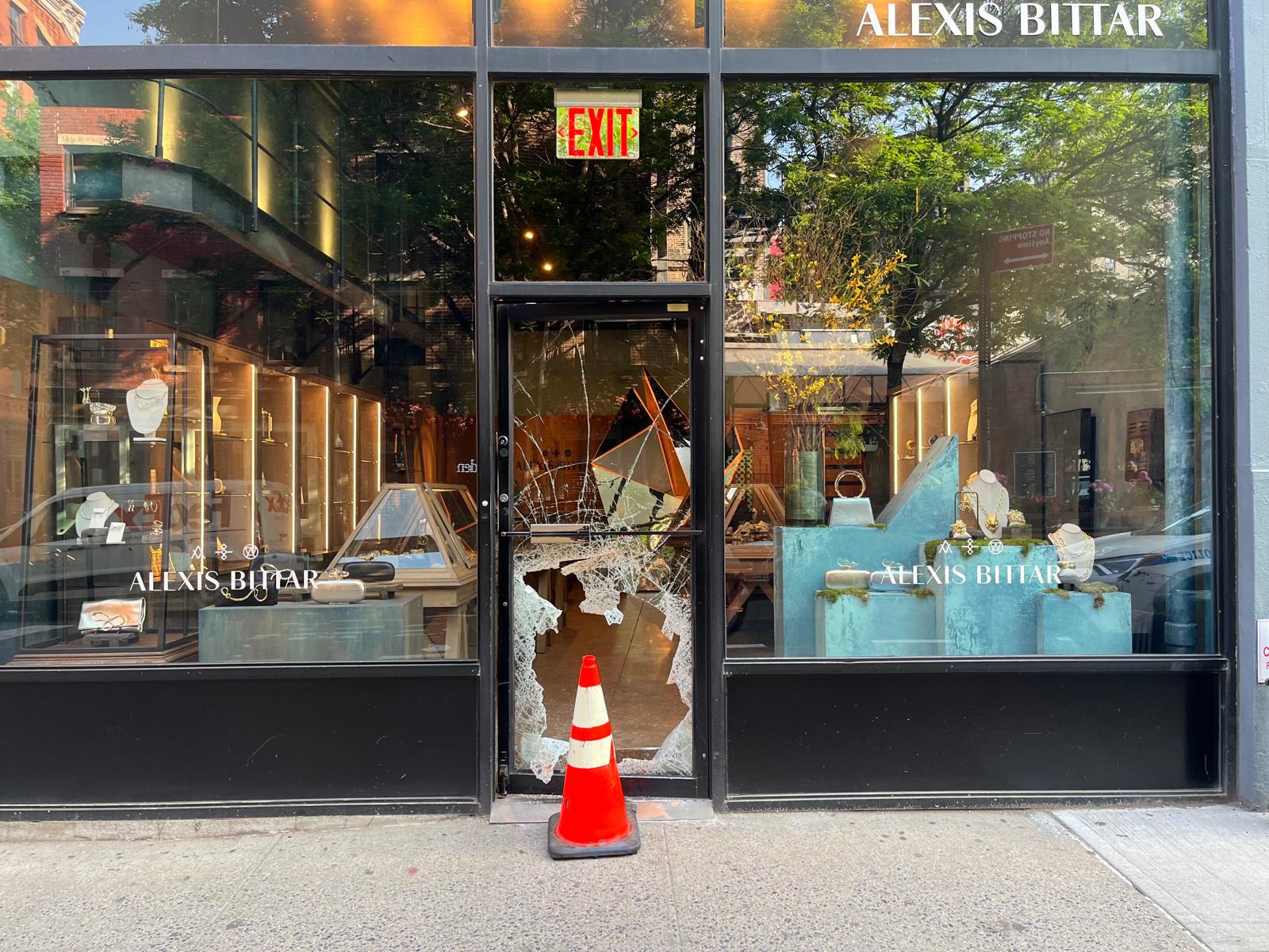 a broken glass door with a traffic cone in front of it
