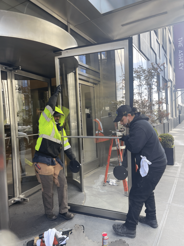 a man in a reflective vest holding a bar to a glass door